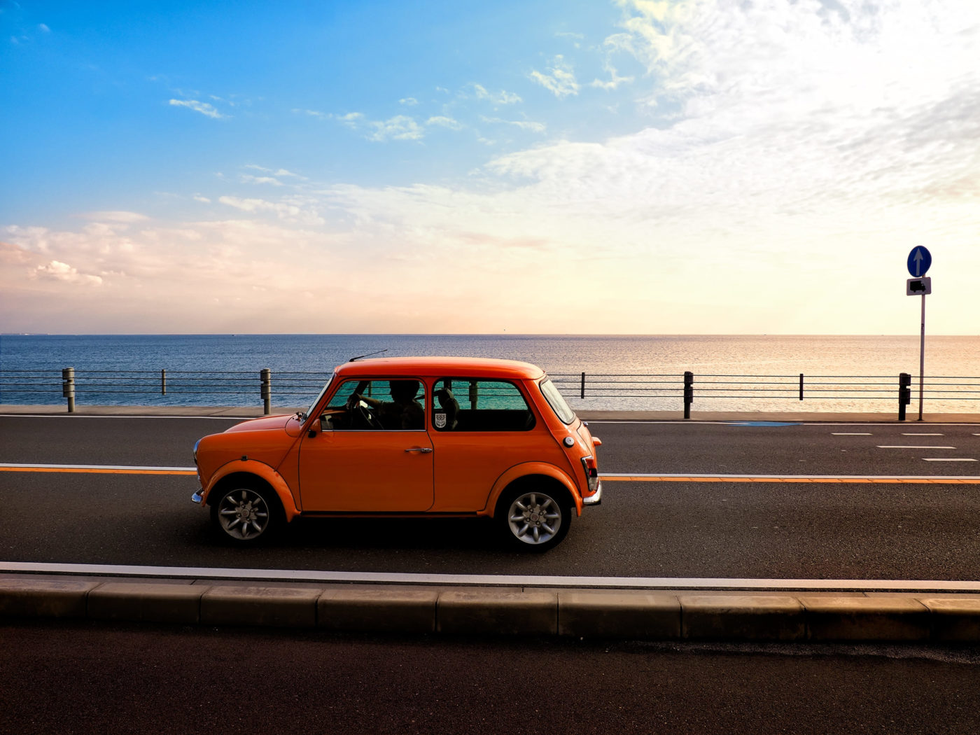 orange car on the road by the beach