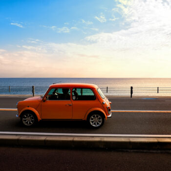orange car on the road by the beach